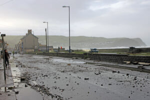The aftermath of the 2014 storm leaves stones and water across the road