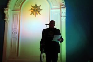 Silhouette of a man on stage telling a story in front of a gold star