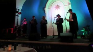 Five people read a short play from a stage