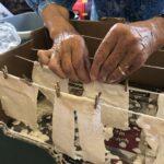 Hands peg tiny washing on to tiny washing lines
