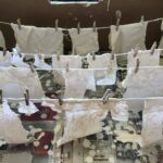 Tiny white clothes dipped in plaster of Paris hang on tiny washing lines to dry.