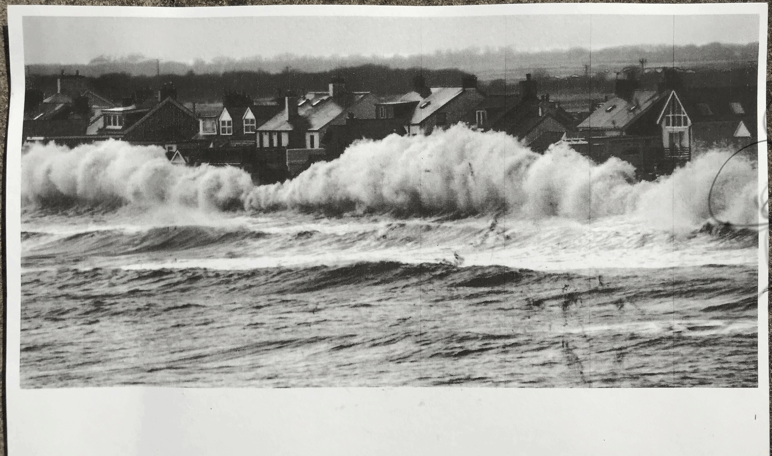 Waves break close to the houses in a big sea in Borth