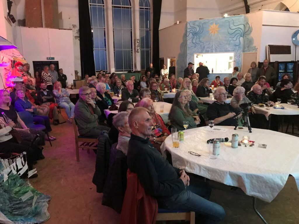 People sit at tables listening to the story tellers