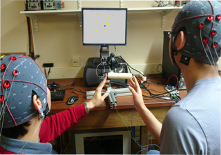 two people with eeg caps pointing at a screen