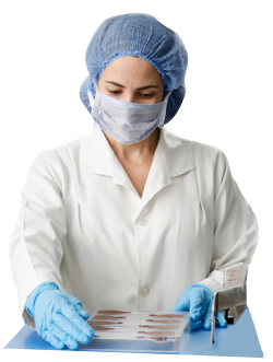 Medical researcher wearing protective equipment and managing a group of vials in a laboratory.