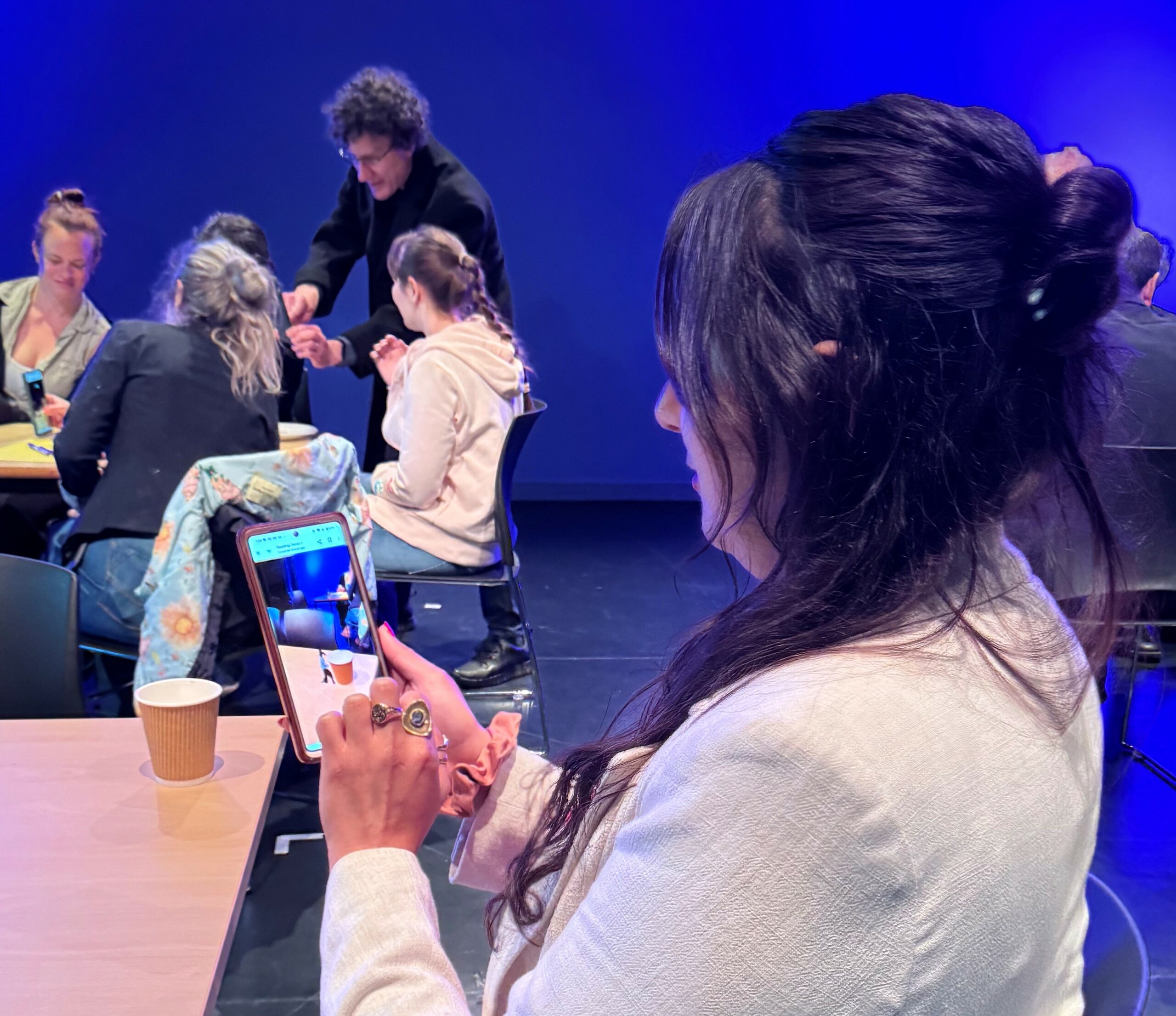 A participant in the foreground views the cup in front of them in AR