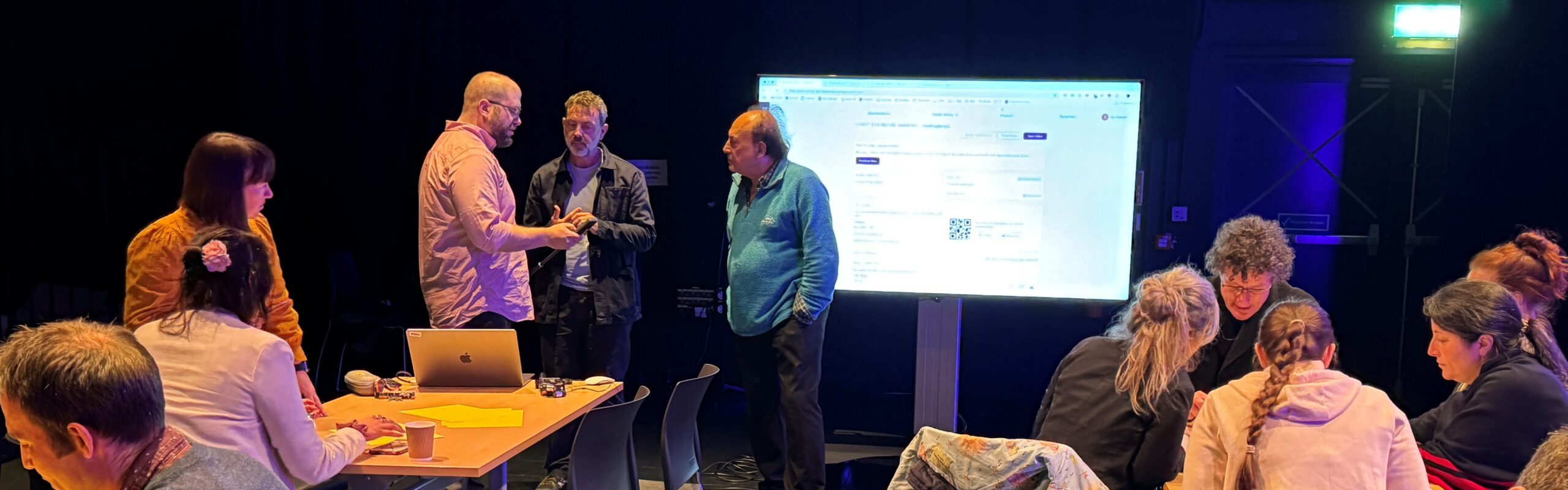 Groups of participants in discussion, with tables and a presentation