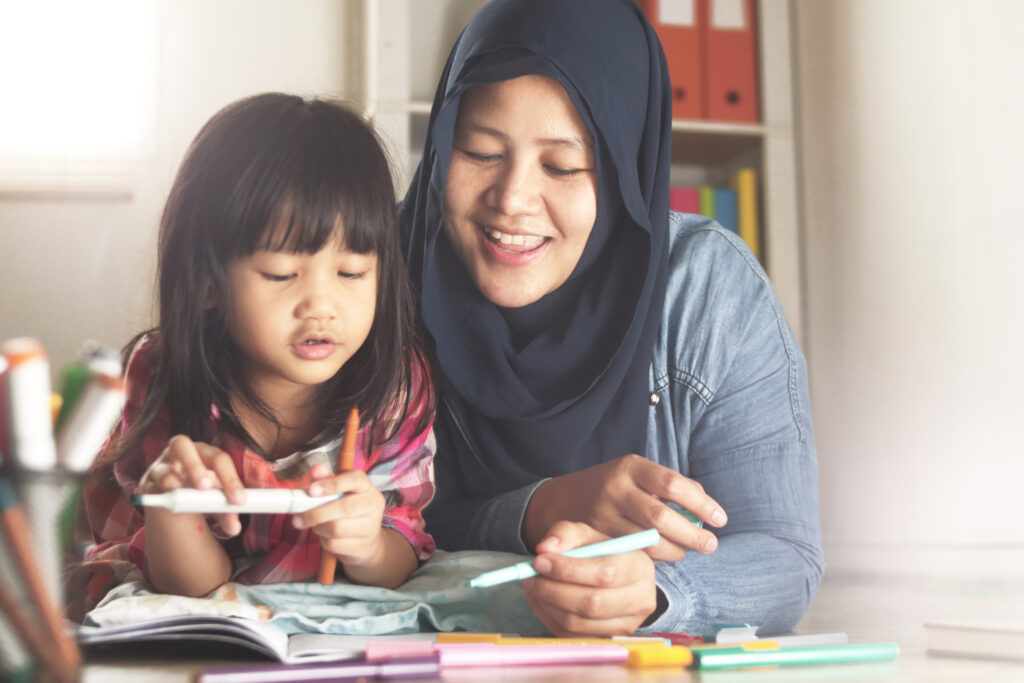 Asian Muslim mother drawing with her daughter,