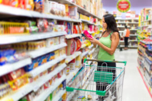 A woman reading the ingredients on a food packet at the supermarket.