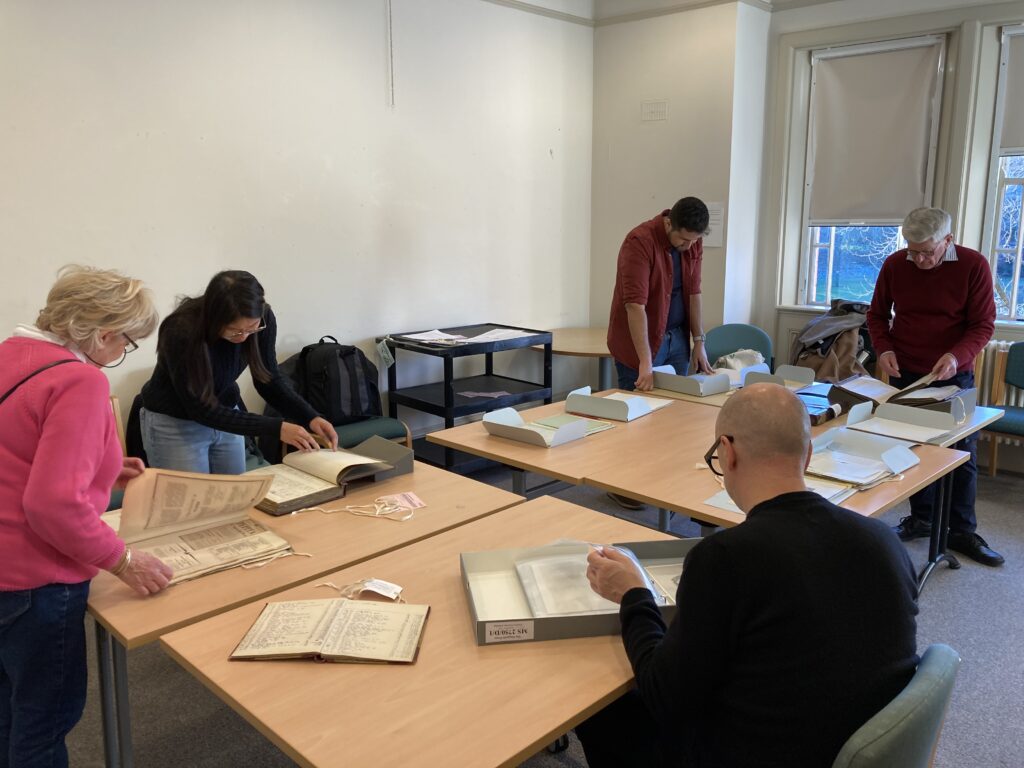 Five volunteers around a table reading books and letters from the twentieth century.