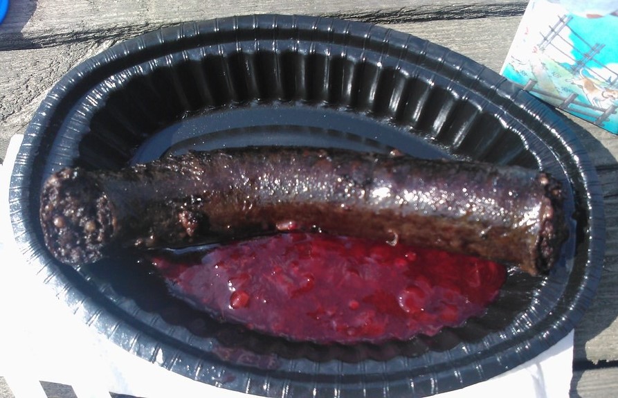 blood sausage with lingonberry sauce on black paper plate