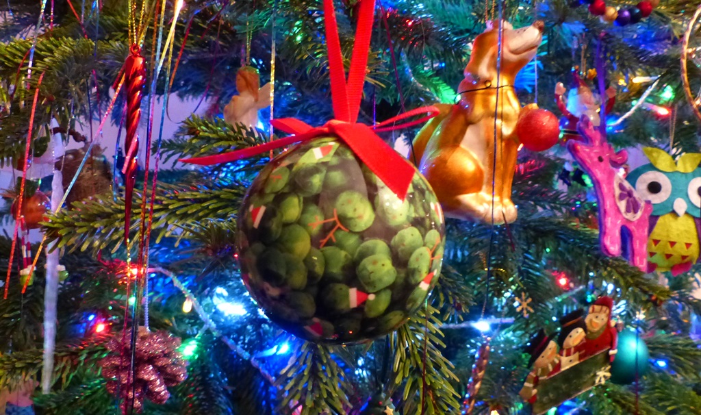 Detail of gaudy christmas tree decorations featuring a sprout bauble