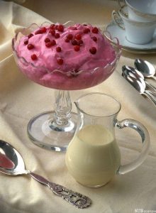 Glass dish on glass stem containing pink whipped dessert topped with red berries
