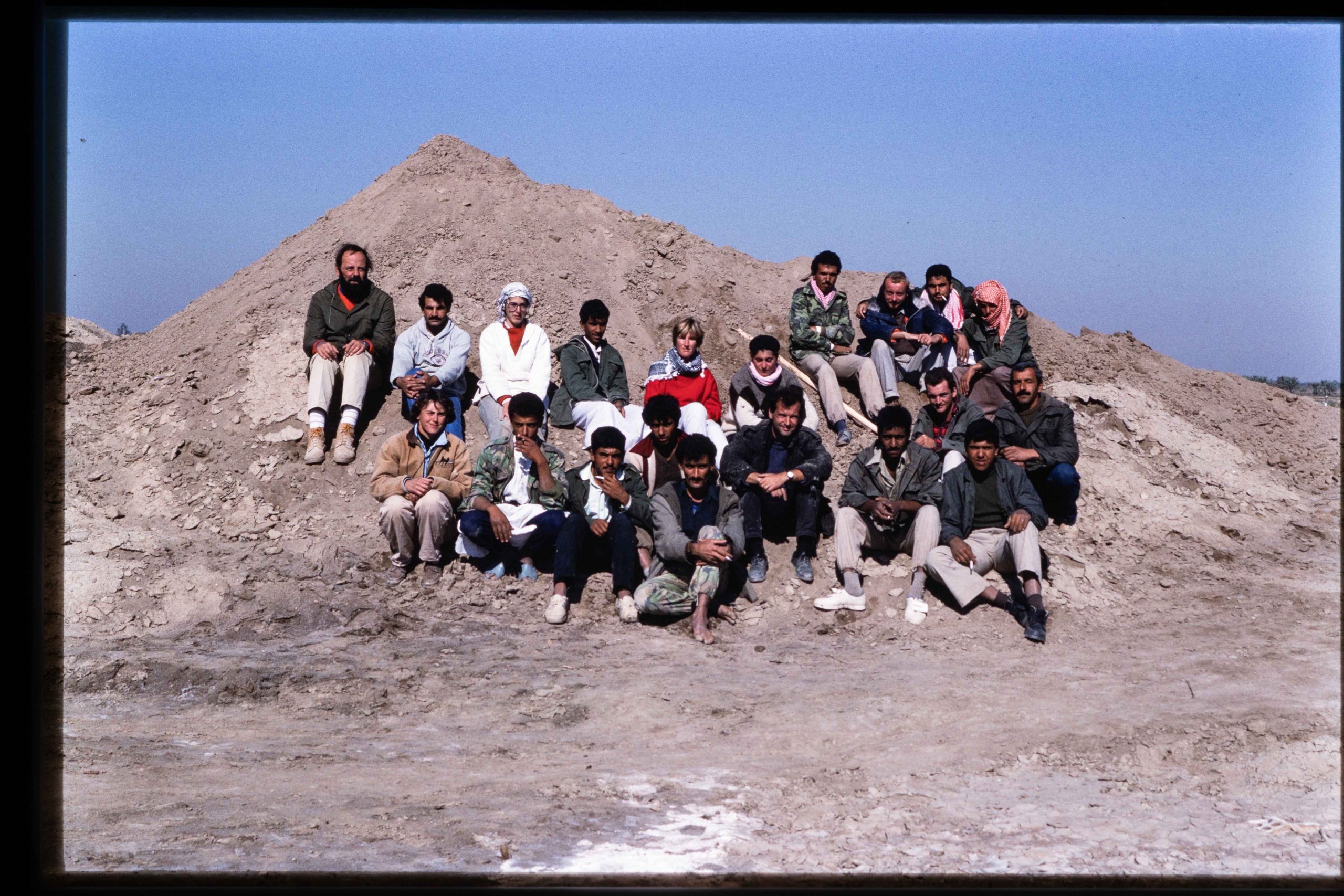 A group of people sitting in front of a mound of earth