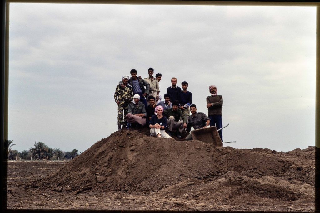 A group of people standing on top of a mound of earth (a spoil heap) posing for a photograph