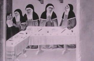 Six medieval nuns sitting around a dining table. Four of the nuns appear to be in discussion, one is praying and one looking upwards.