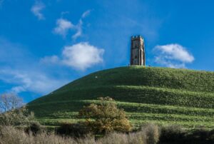Image of Glastonbury Tor with St Michael's Tower, a three-storey tower with corner buttresses and perpendicular bell openings