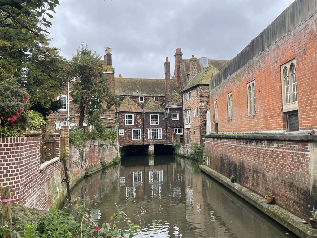 Canalised river with buildings to each side and bridge with buildings crossing it