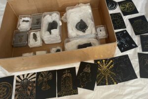 A box containing leaden pilgrim signs surrounded by engraved artworks based on them