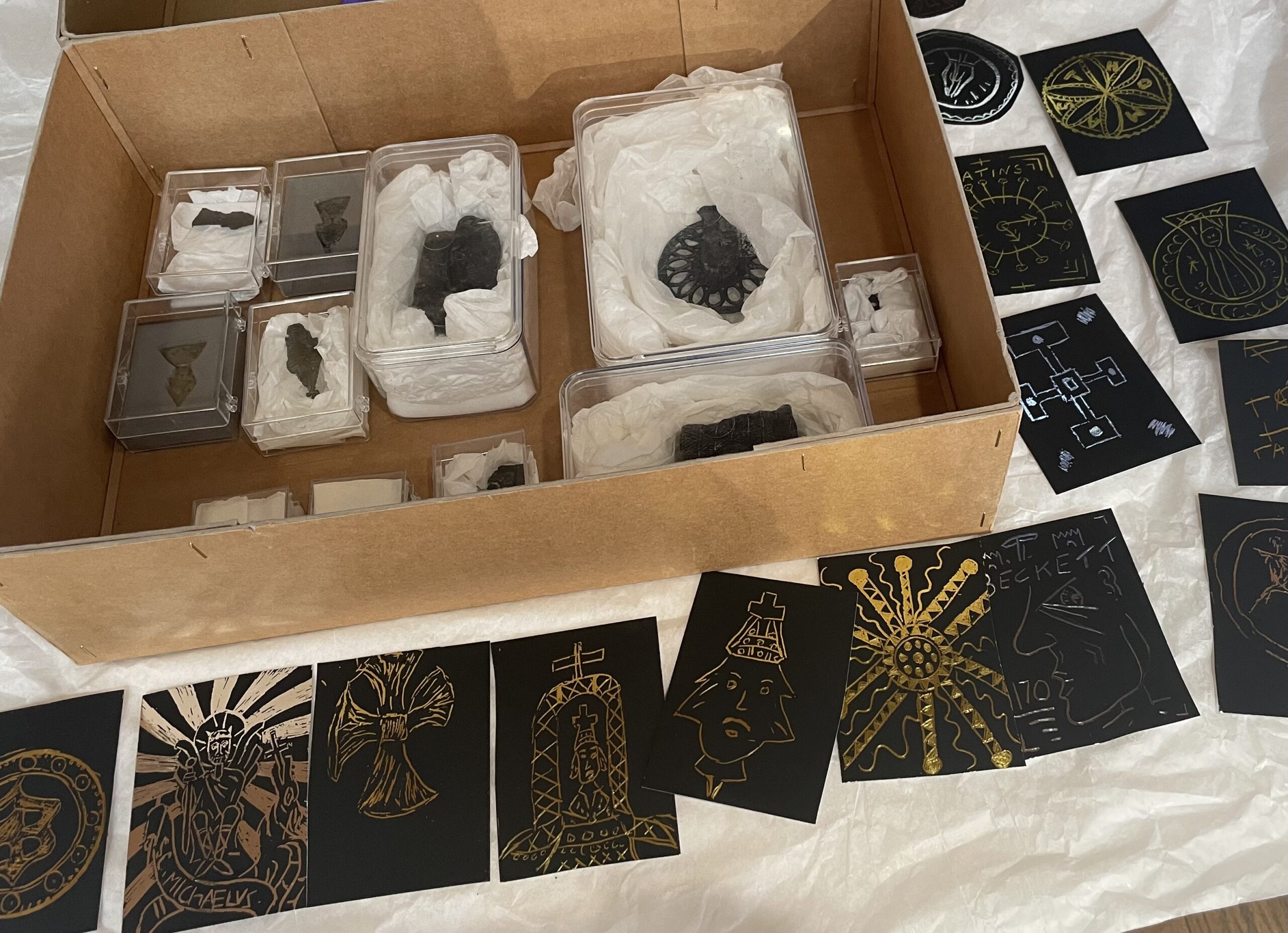 A box containing leaden pilgrim signs surrounded by engraved artworks based on them