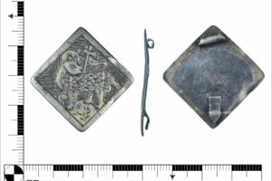 Silver square or lozenge shaped silver panel featuring an engraved Lamb and cross. Full description at https://finds.org.uk/database/artefacts/record/id/992821