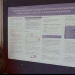 Sam Szade standing next to her poster