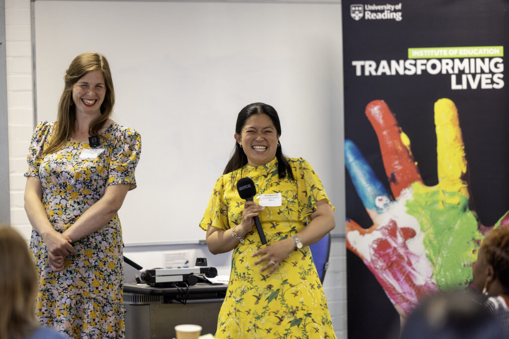 Two women standing and laughing in front of an audience