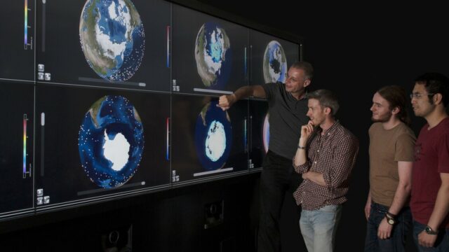 a man explaining a satellite image of earth to a group of students