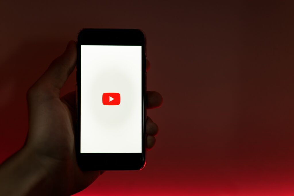 Hand holding a smartphone showing the YouTube app