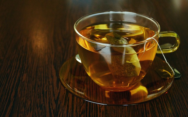 A cup of tea – a glass cup with a teabag and hot water on a table.
