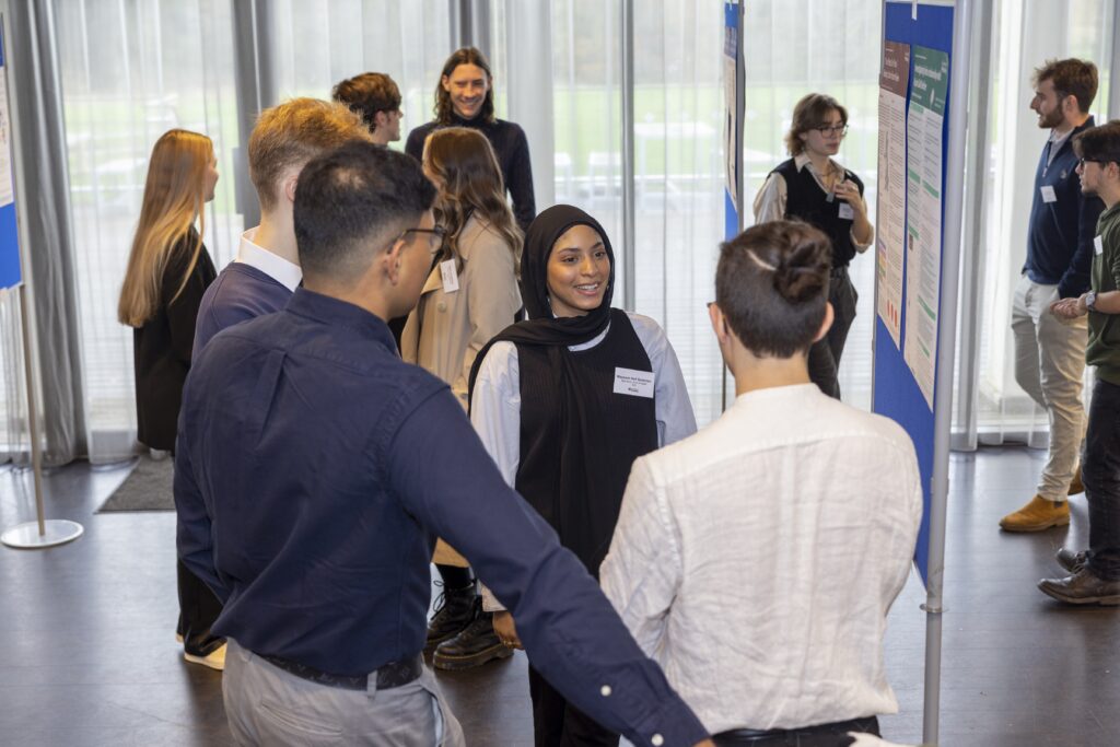 Students chat beside poster boards at the showcase for the Undergraduate Research Opportunities Programme