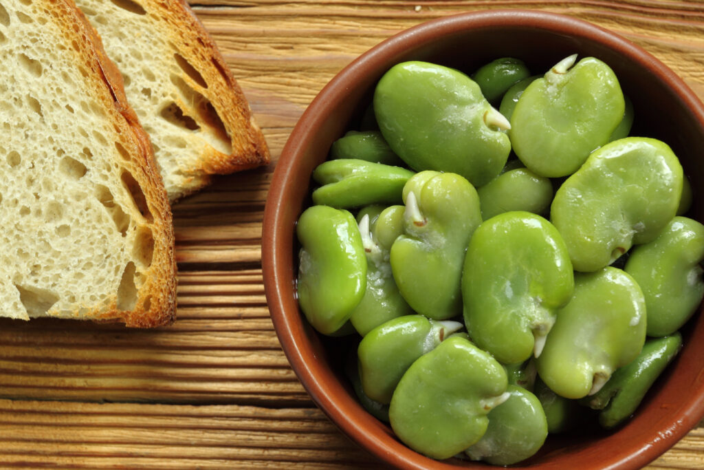 Broad beans in bowl and bread.