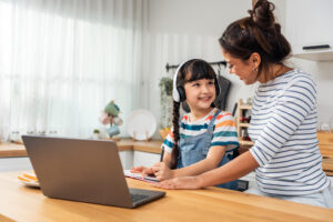 Girl with headphones and laptop smiles at mother