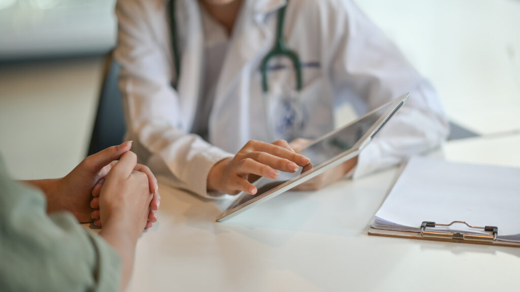 A doctor showing a patient some information on a digital tablet