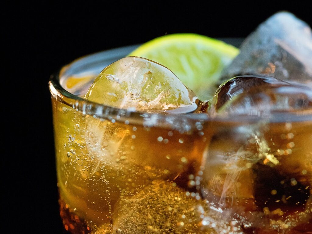 a close-up of a glass of coke with ice and lemon