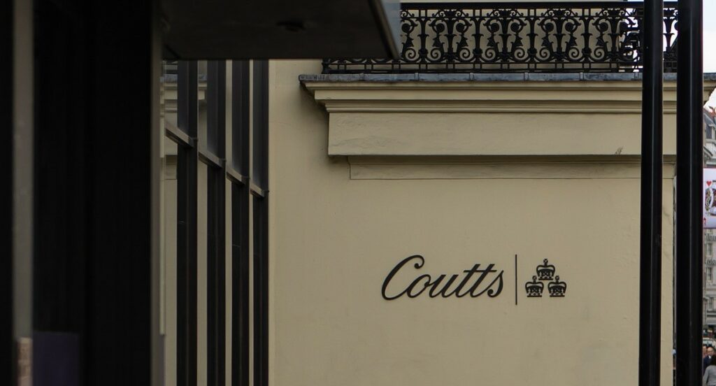 Coutts sign. Black cursive script against a cream wall.