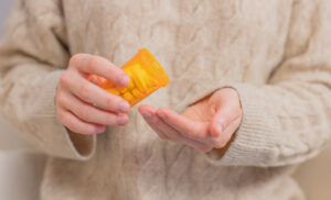 Person dispensing aspirin from a yellow pill bottle.