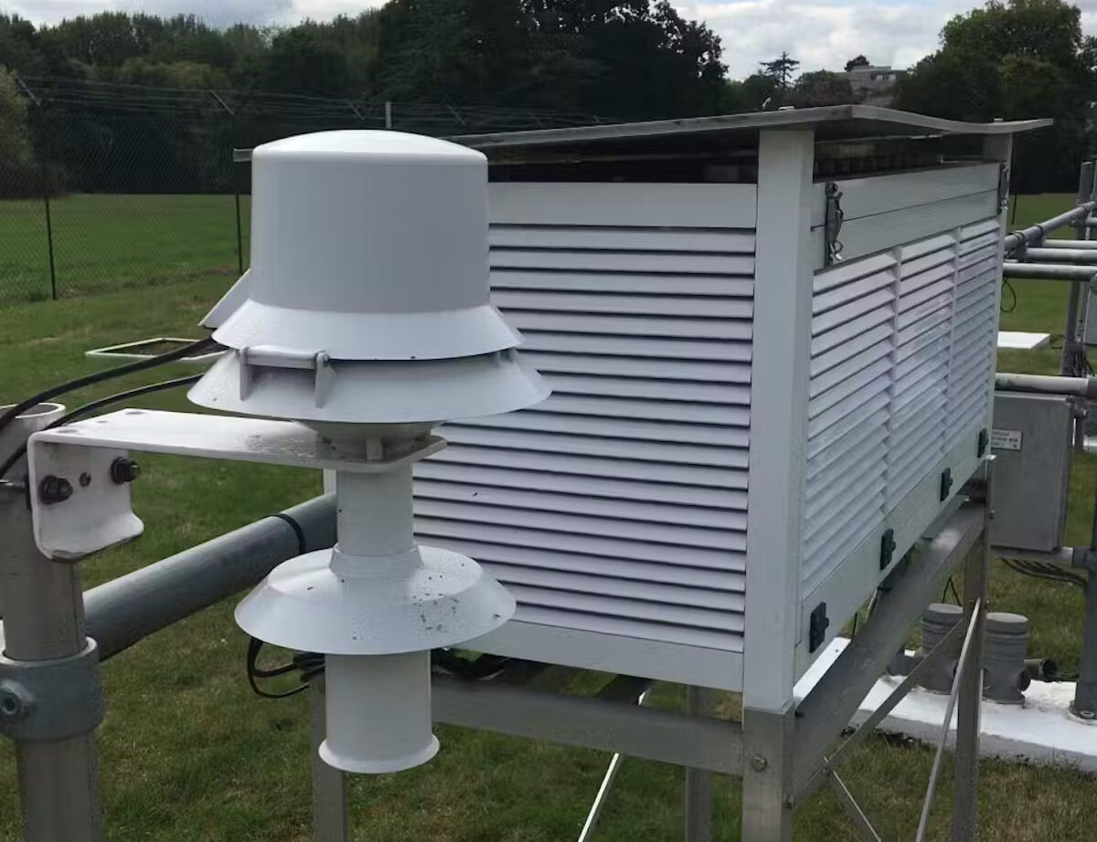 A Stevenson screen - a louvred white box - next to a modern thermometer