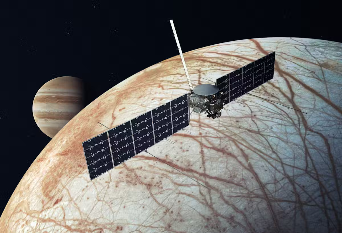 A graphic of the Europa Clipper satellite flying past Europa, with Jupiter in the background