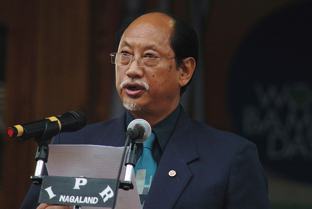 An Indian man with a white goatee speaks into 2 microphones with the text 'IPR Nagaland' displayed.