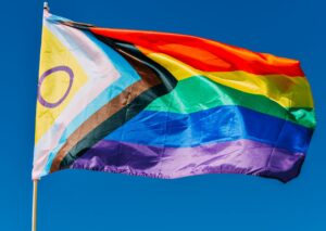 LGBTQ progress rainbow flag waving in the wind against blue sky