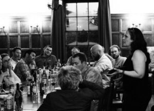 A lady presenting to people in a room (black and white photo)