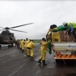 colour photograph of helicopter being loaded with emergency supplies, helicopter background left, truck right foregroudn